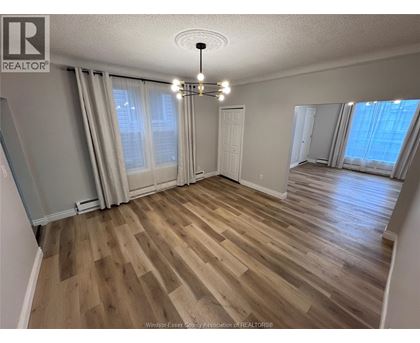 A room with wooden flooring and a chandelier.