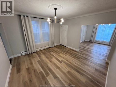 A room with wooden flooring and a chandelier.