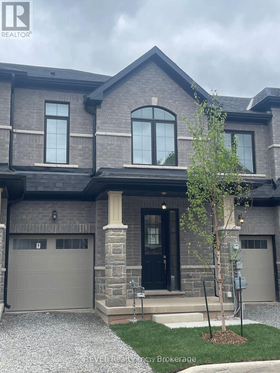 A grey house with a black front door and a tree in front.