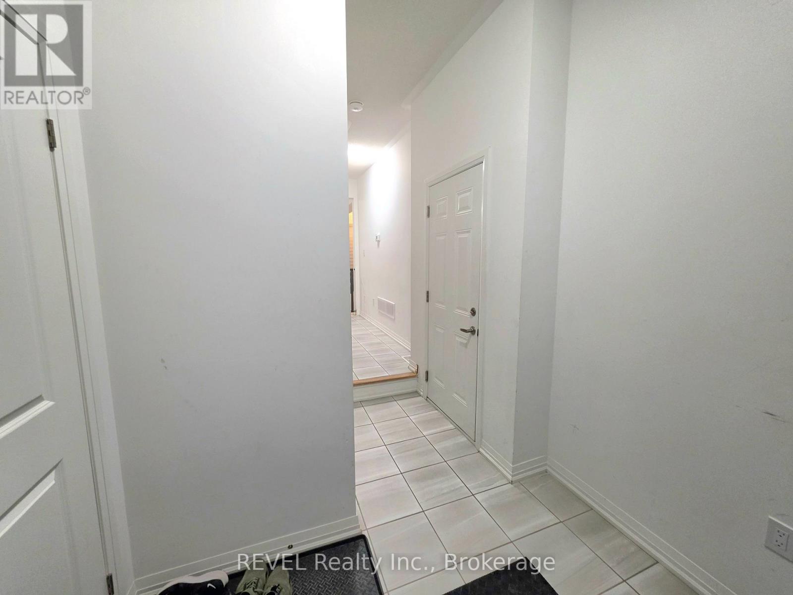 A hallway with white walls and a tiled floor.