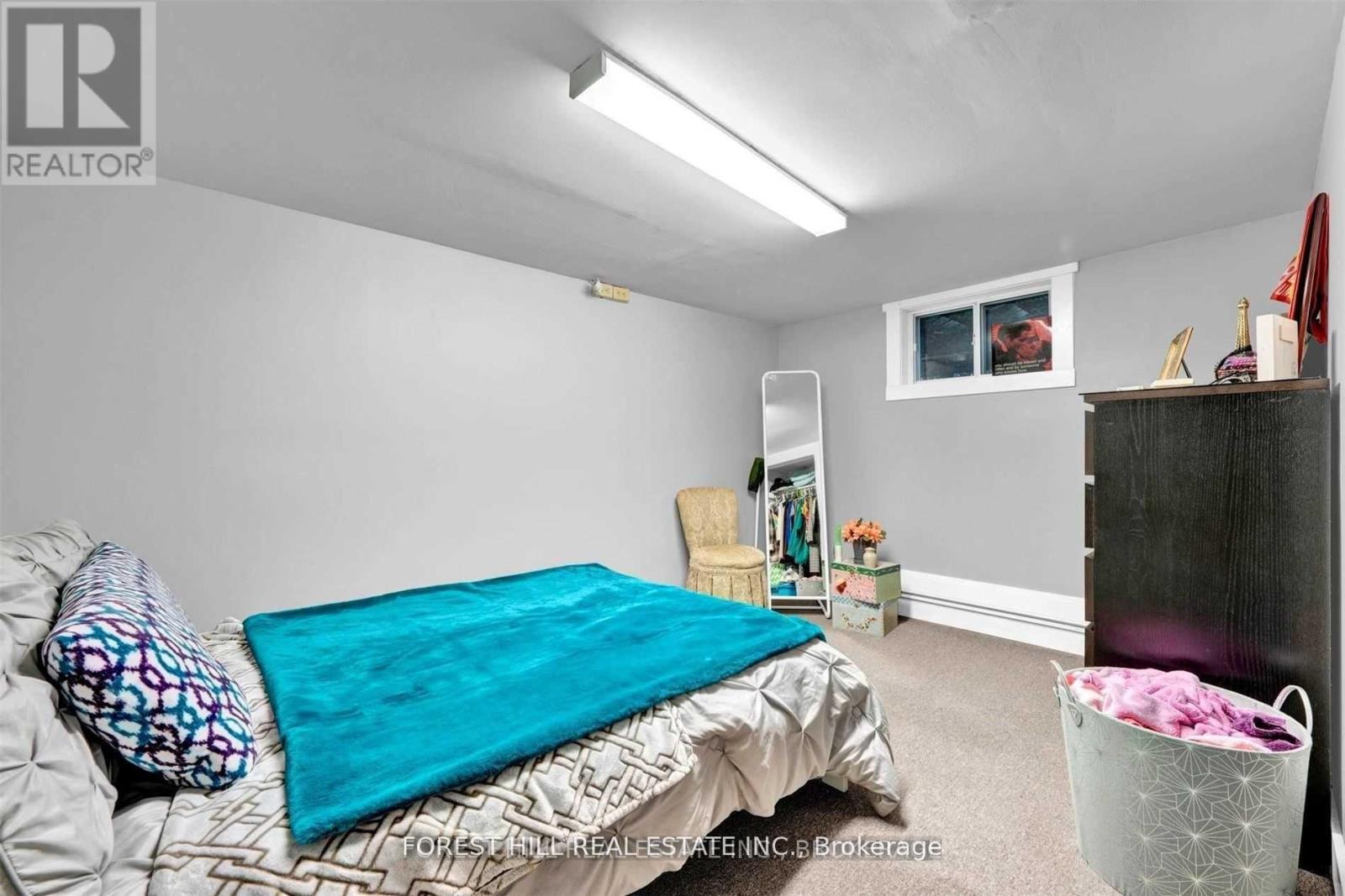 A bedroom with a bed, a chair, a shelf, and a laundry basket.