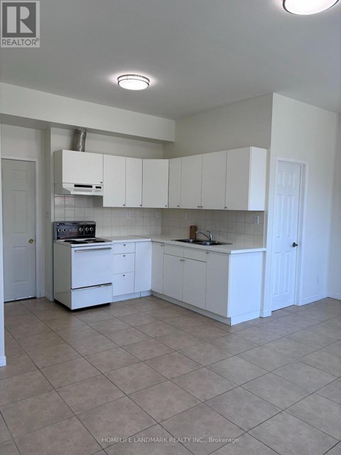 A kitchen with white cabinets and a tile floor.