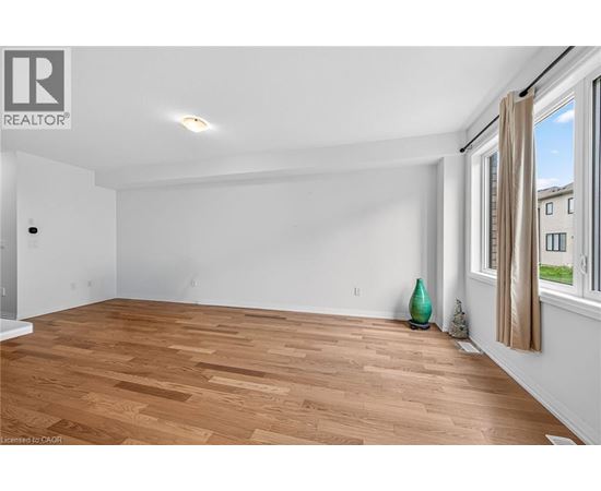 A room with wooden flooring and a window with a view of buildings outside.