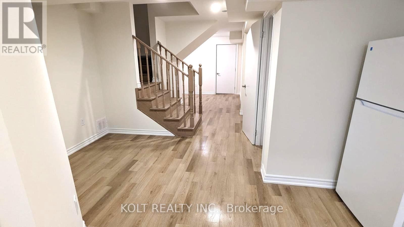 A hallway with a staircase and a refrigerator.