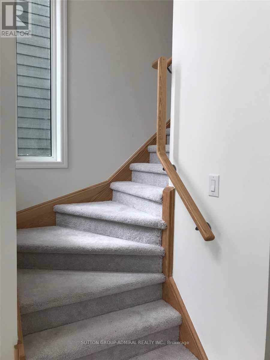 A staircase with a wooden handrail and grey carpeted steps.
