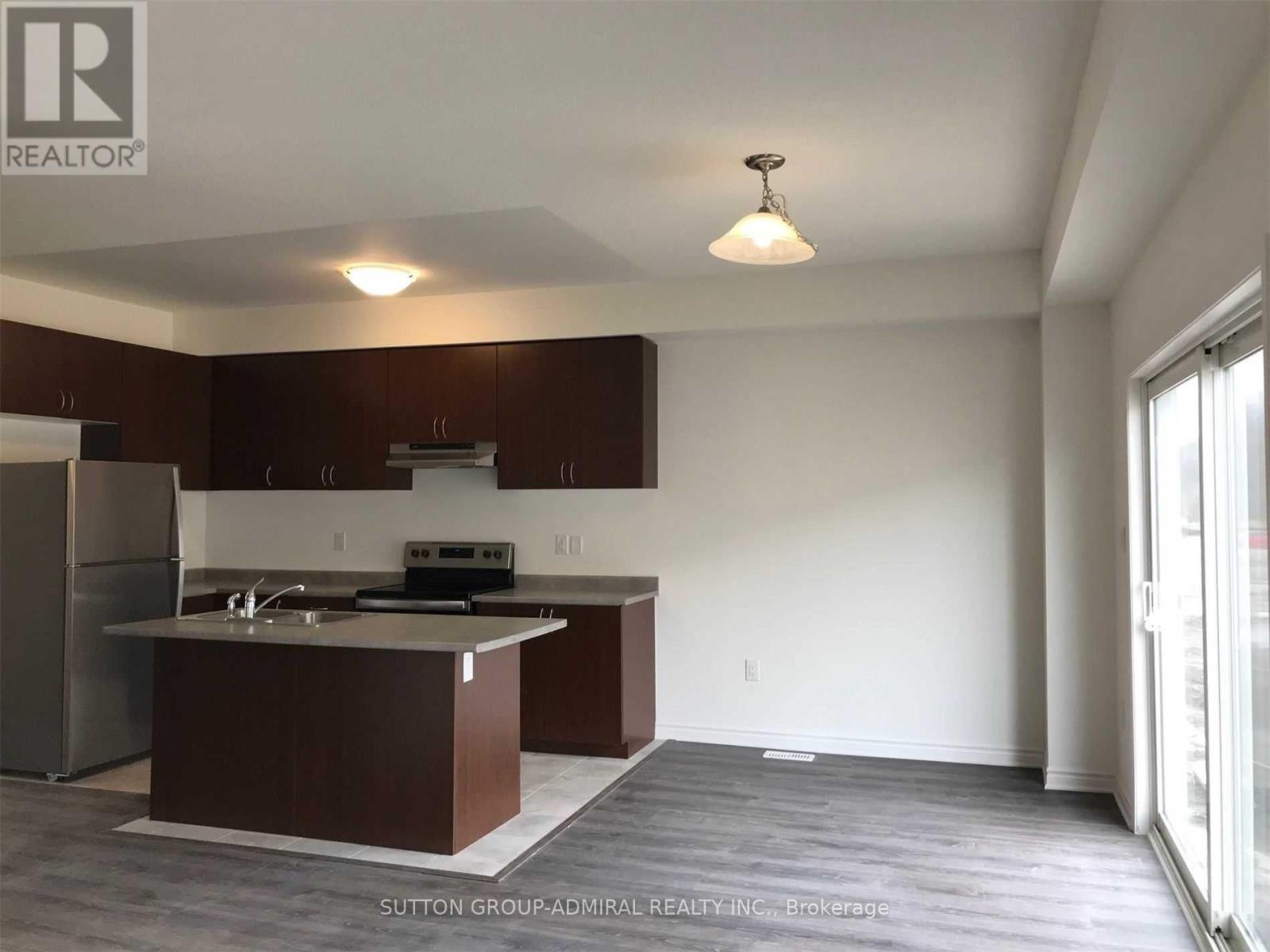 A kitchen with brown cabinets and a stainless steel refrigerator.