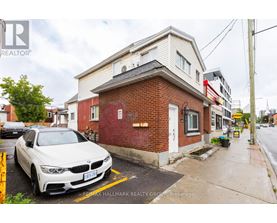 A white BMW is parked in front of a red brick building.