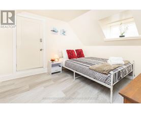 A bedroom with a bed, nightstand, and a window.