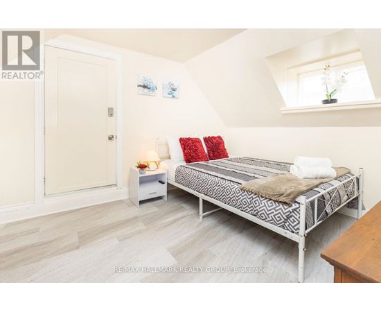 A bedroom with a bed, nightstand, and a window.