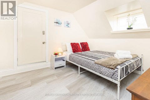A bedroom with a bed, nightstand, and a window.