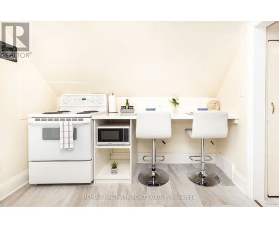 A kitchen with a white oven and microwave, a white table with two chairs, and a plant on the counter.