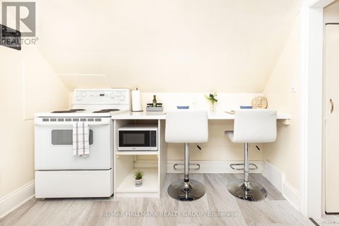 A kitchen with a white oven and microwave, a white table with two chairs, and a plant on the counter.