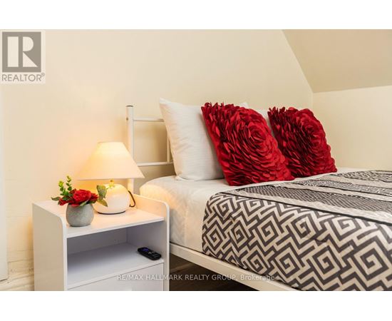 A bedroom with a bed, a nightstand with a lamp, and a vase of flowers.