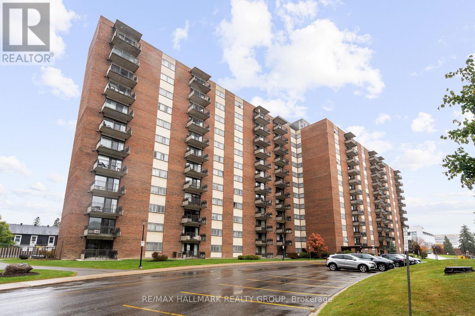 A tall apartment building with a parking lot in front.
