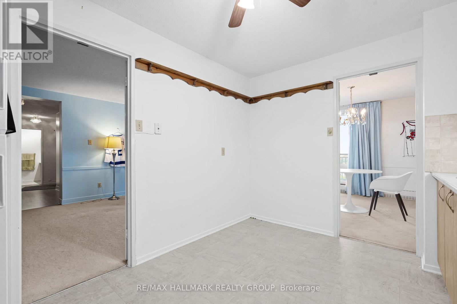 A spacious room with a ceiling fan and a doorway leading to another room.