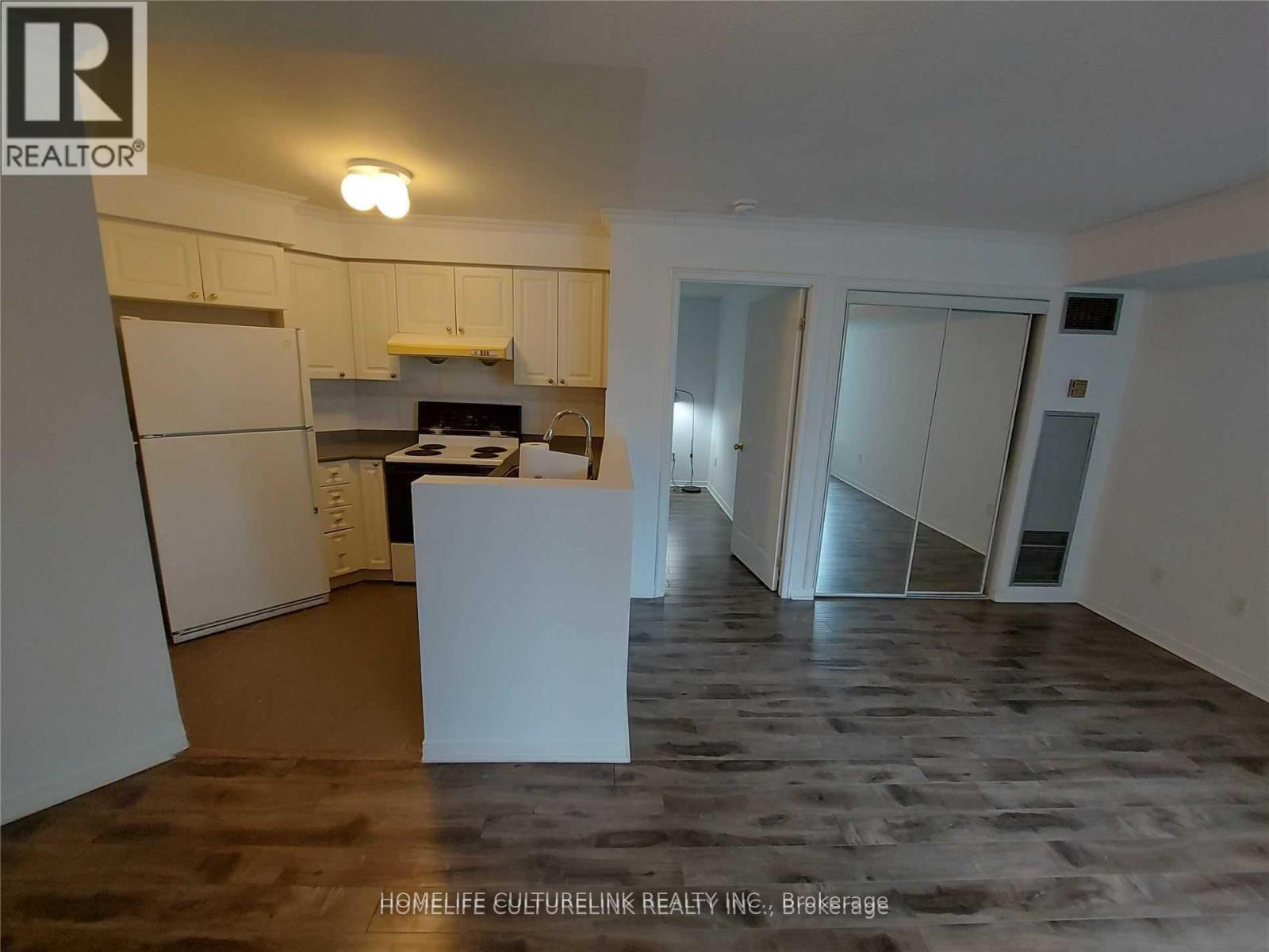 A kitchen area with a refrigerator, a counter, and a dining table.