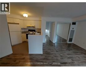 A kitchen area with a refrigerator, a counter, and a dining table.
