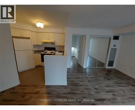 A kitchen area with a refrigerator, a counter, and a dining table.