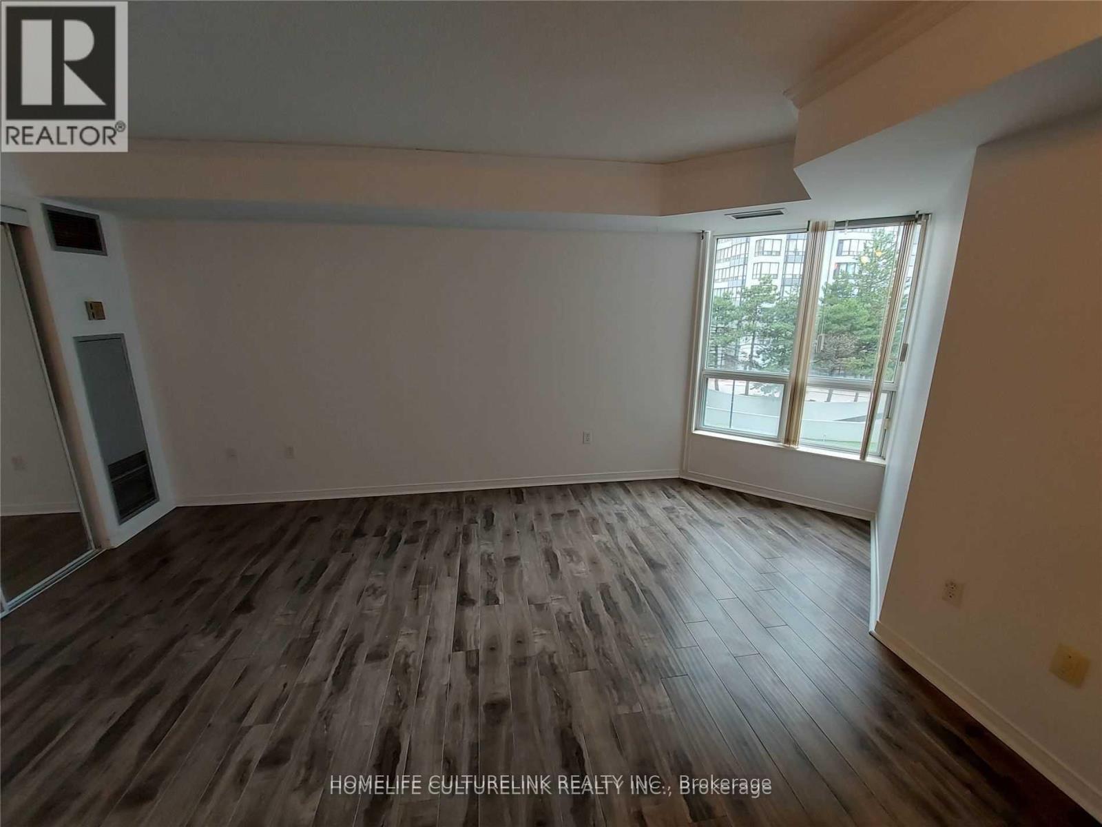 A room with wooden flooring and a large window.