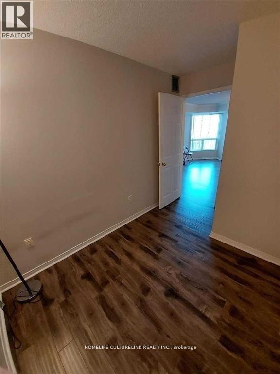 A room with wooden floors and a brokerage sign on the wall.