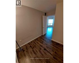 A room with wooden floors and a brokerage sign on the wall.
