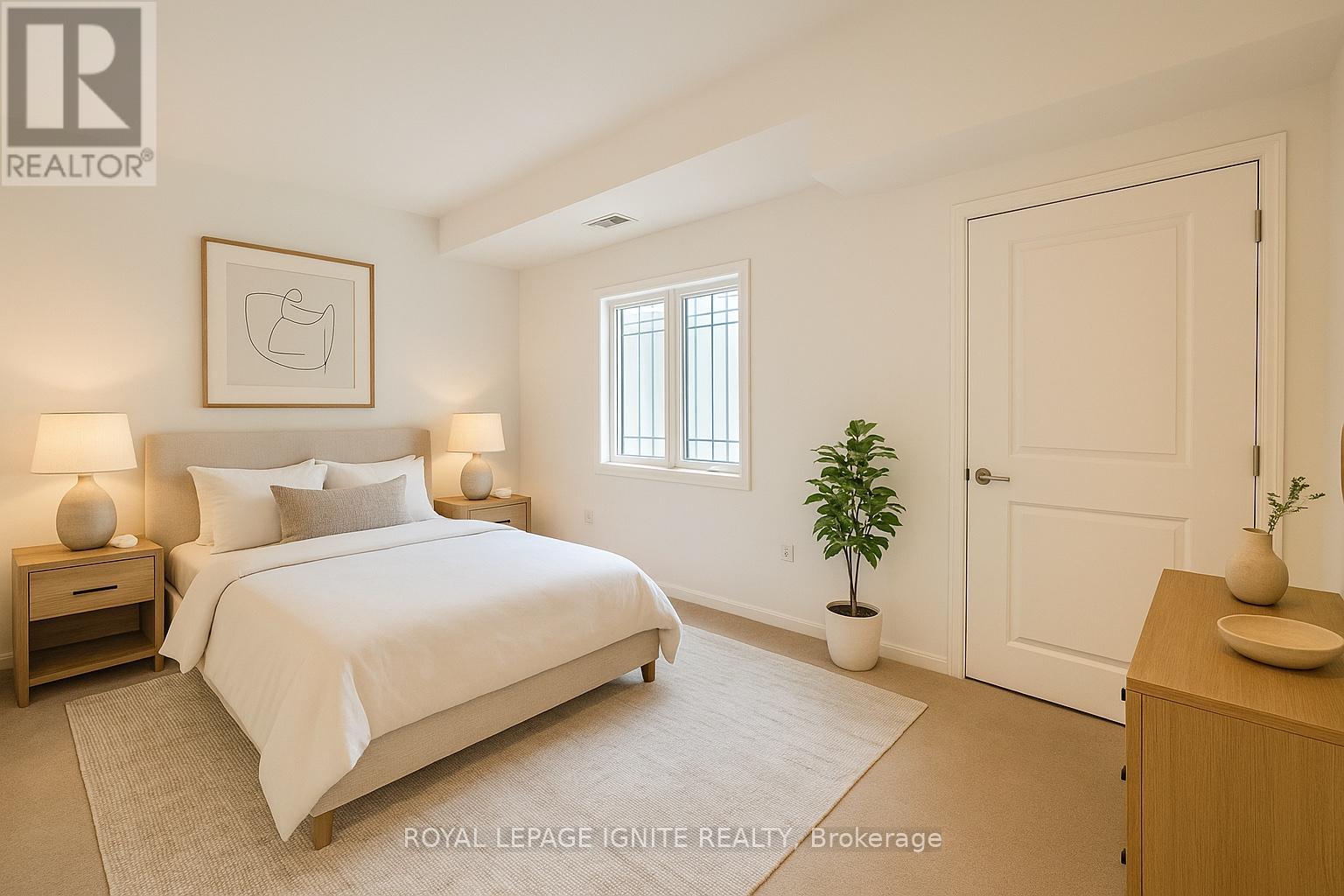A bedroom with a large bed, a nightstand, a lamp, a plant, and a door.