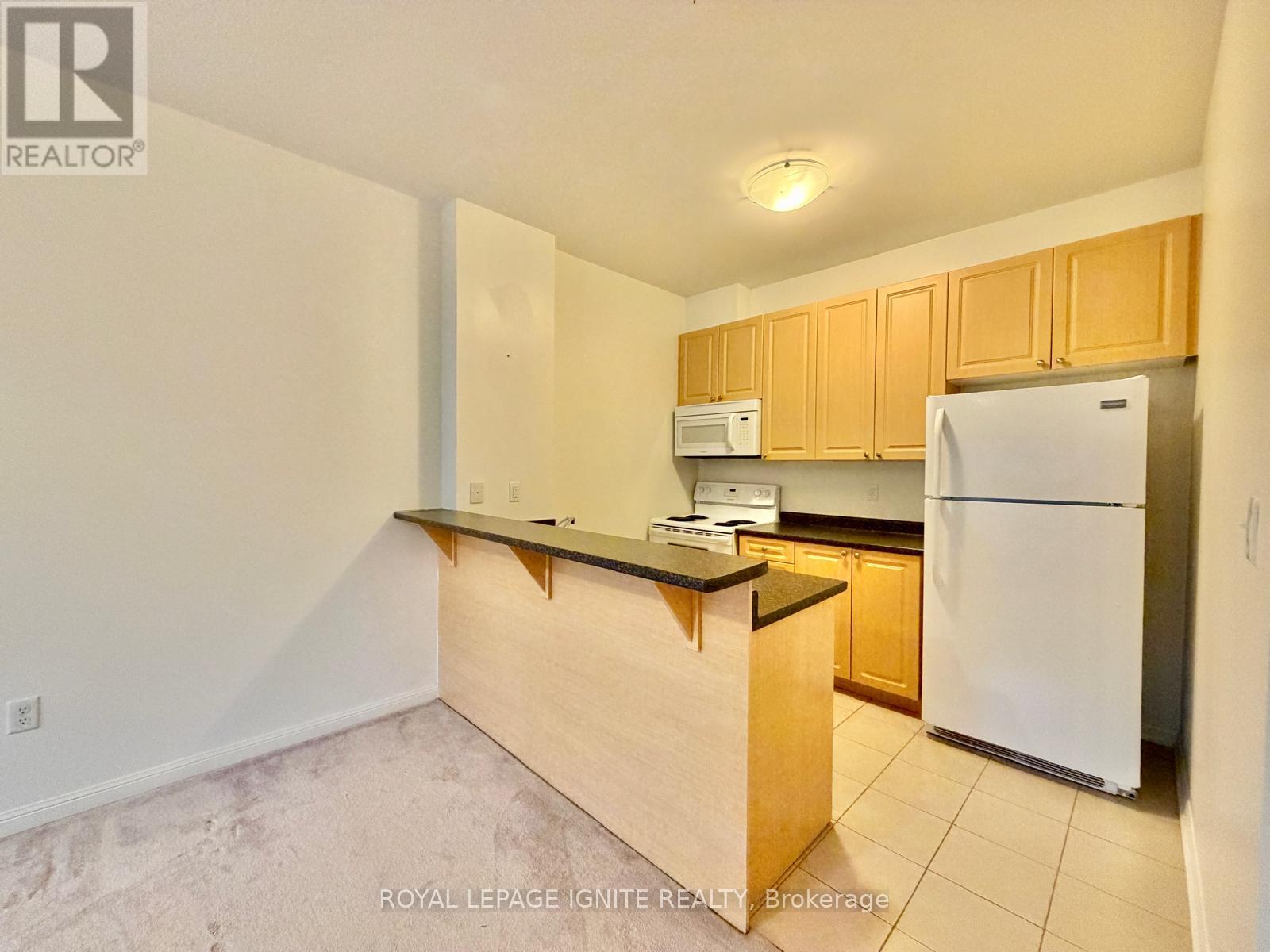 A kitchen with a white refrigerator and wooden cabinets.