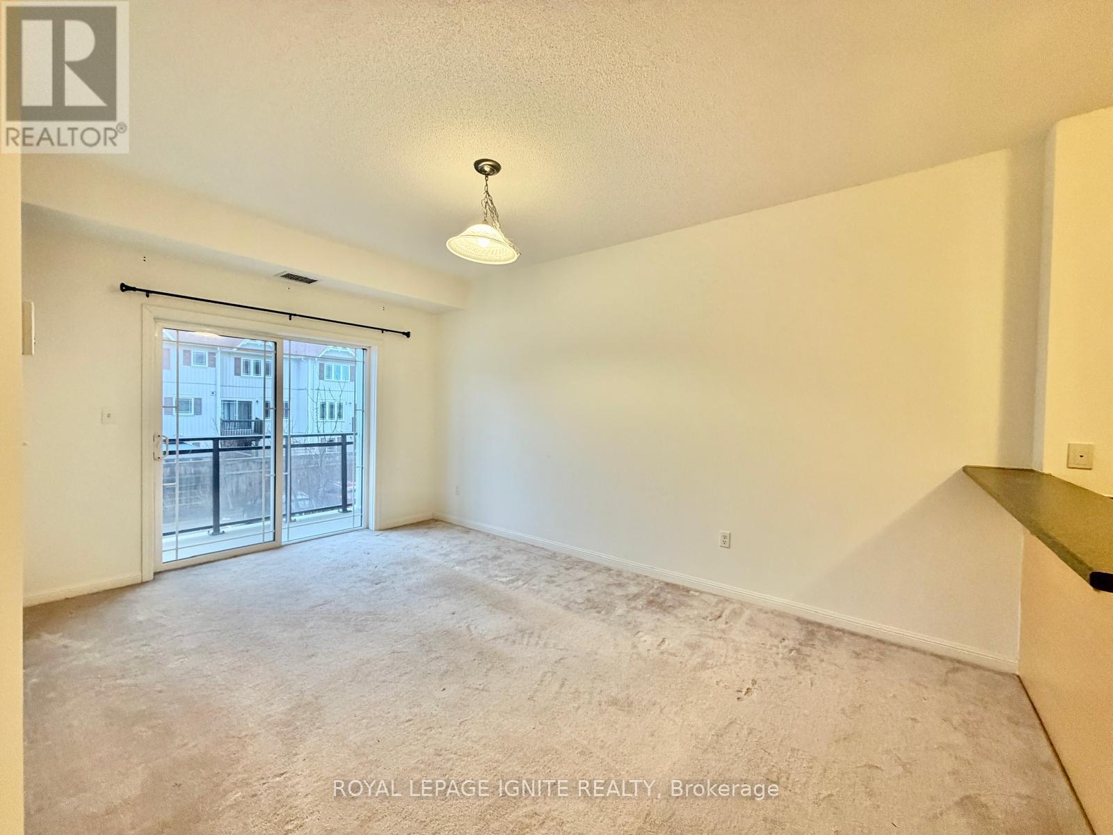 A spacious, empty room with a sliding glass door leading to a balcony.