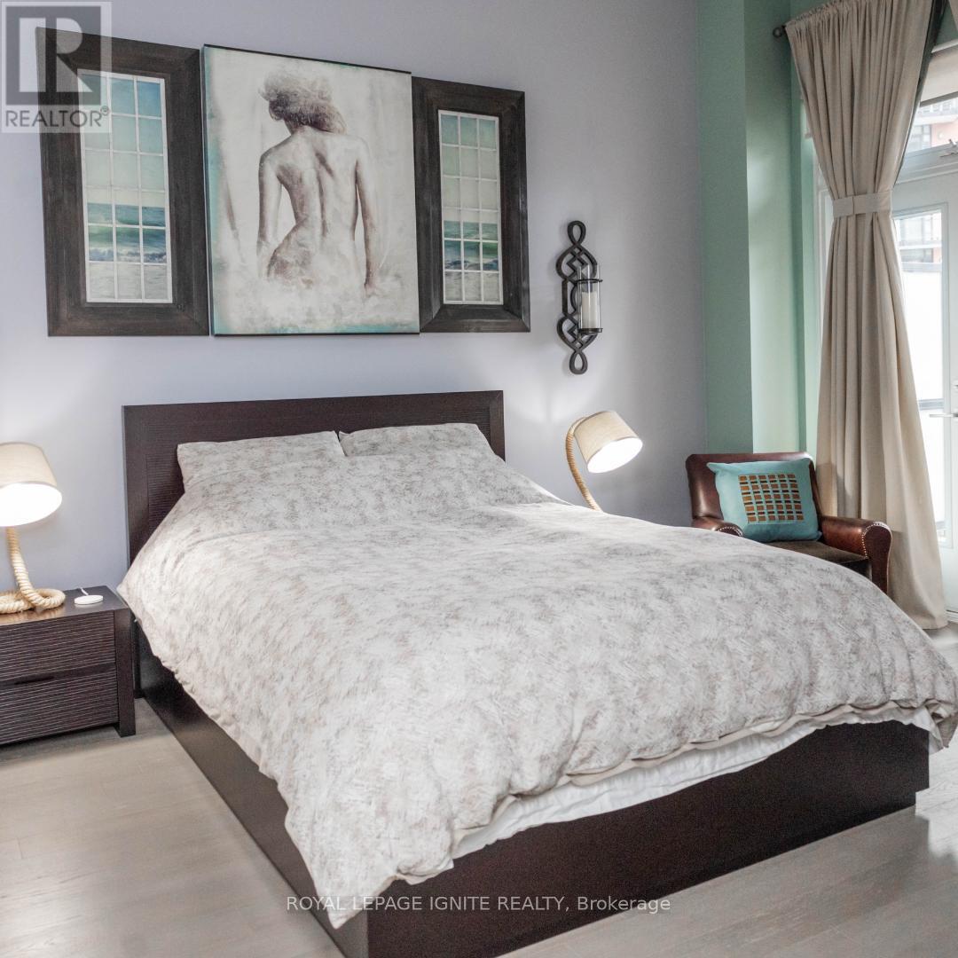 A bedroom with a large bed, a nightstand with a lamp, and a painting on the wall.