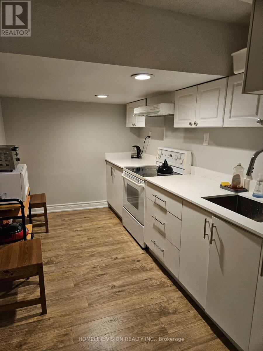 A kitchen with white cabinets and a wooden floor.