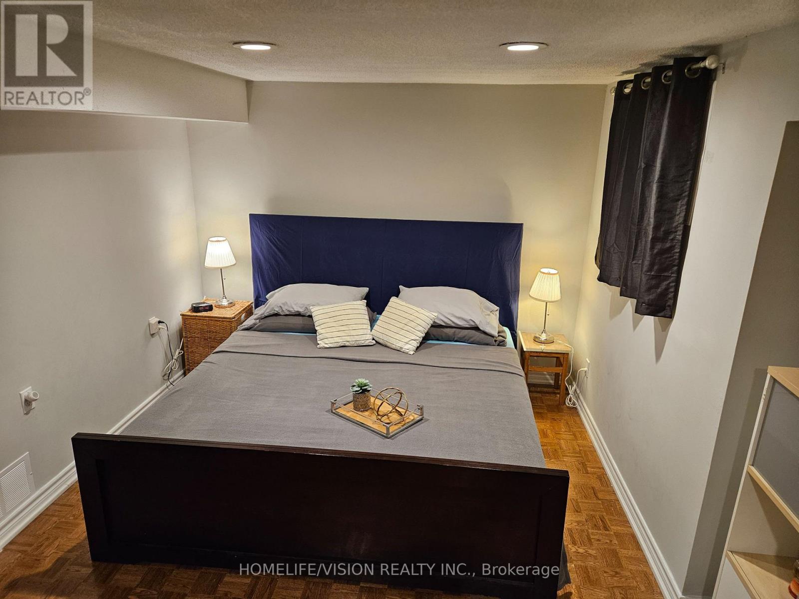 A bedroom with a large bed and a wooden floor.