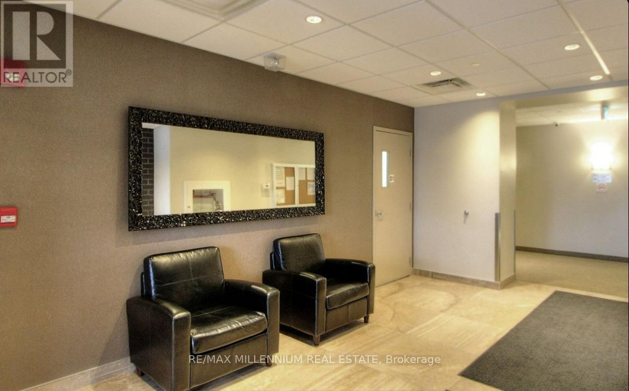 Two black leather chairs are placed in front of a large mirror in a room.
