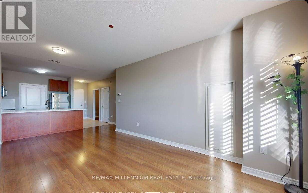 A spacious room with wooden flooring and a large window with blinds.