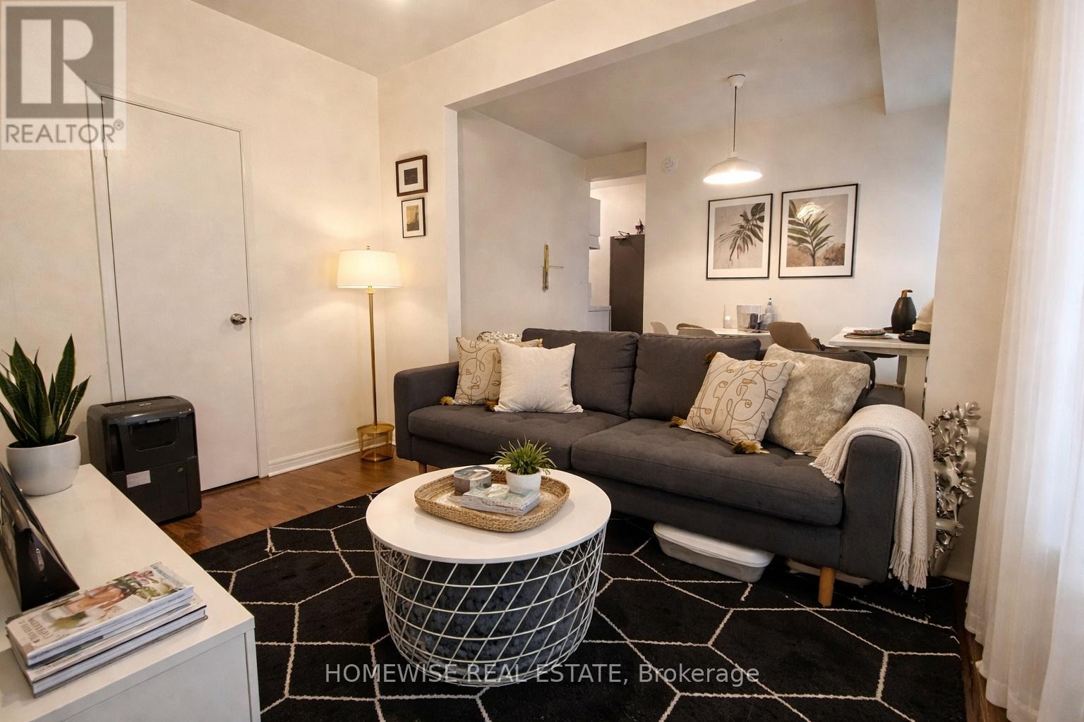 A living room with a grey couch, a coffee table, and a plant.