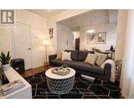A living room with a grey couch, a coffee table, and a plant.