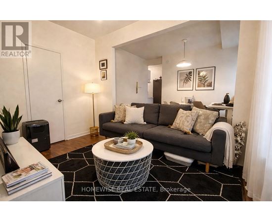 A living room with a grey couch, a coffee table, and a plant.