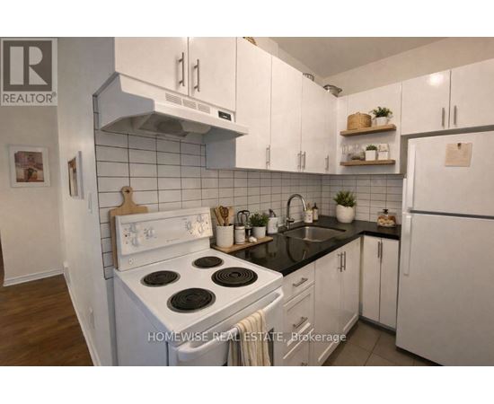 A kitchen with white cabinets and a black countertop.