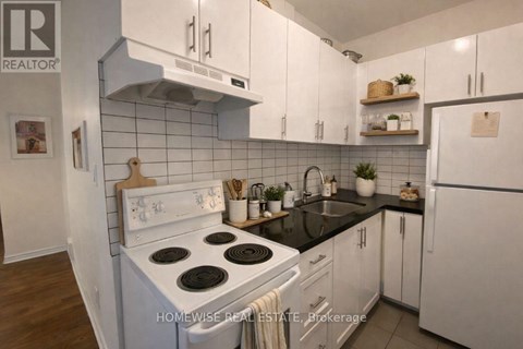 A kitchen with white cabinets and a black countertop.