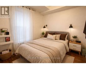 A bedroom with a large bed, a nightstand, and a window with sheer curtains.