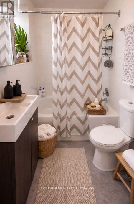 A bathroom with a white toilet, a sink, and a shower curtain with a chevron pattern.