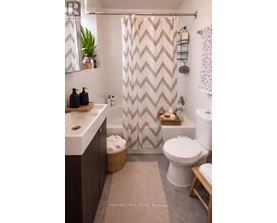A bathroom with a white toilet, a sink, and a shower curtain with a chevron pattern.