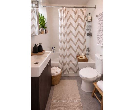 A bathroom with a white toilet, a sink, and a shower curtain with a chevron pattern.