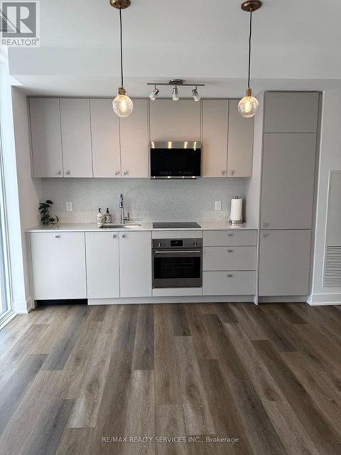 A modern kitchen with white cabinets and a wooden floor.