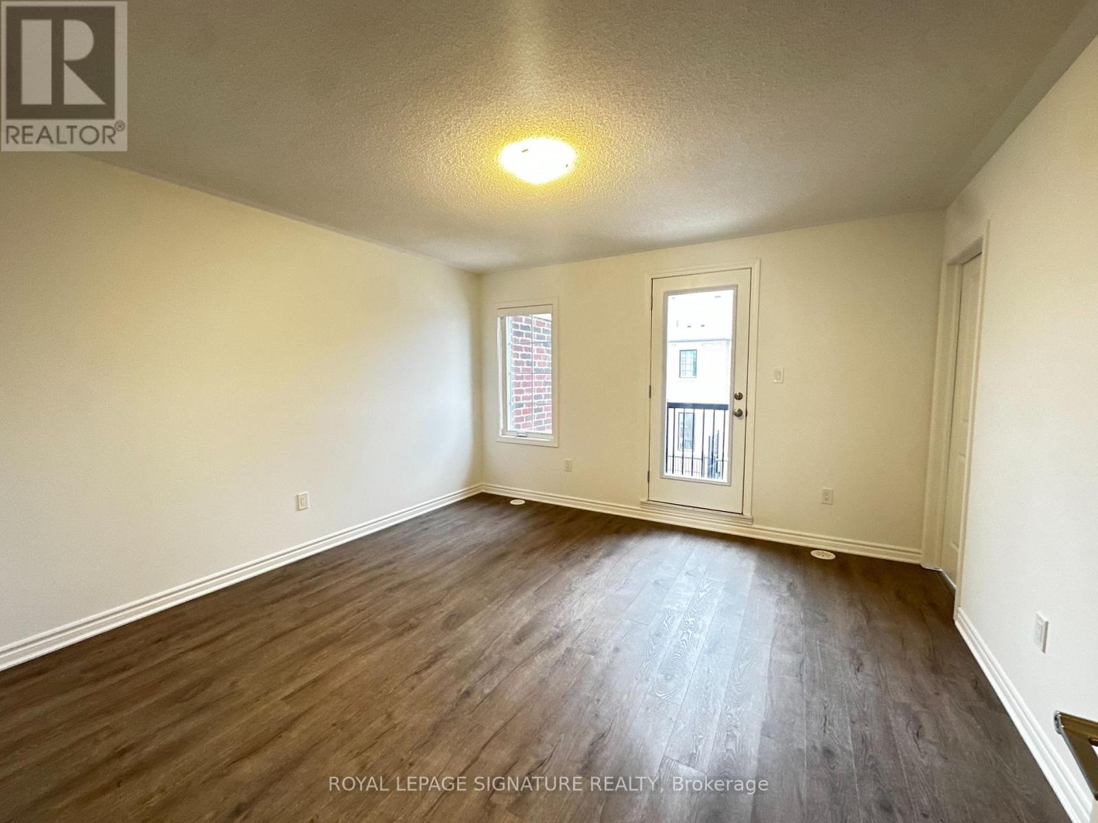A room with wooden flooring and a door leading to a balcony.
