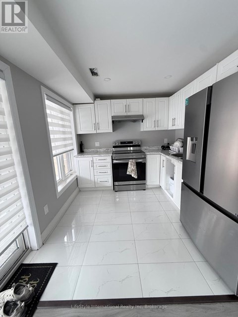 A modern kitchen with white cabinets and a black refrigerator.