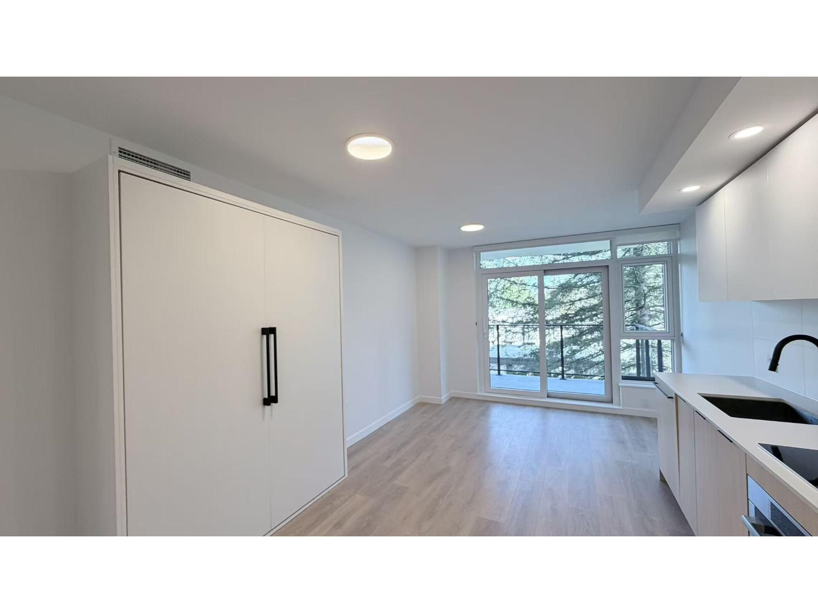 A kitchen with a white fridge and wooden floors.