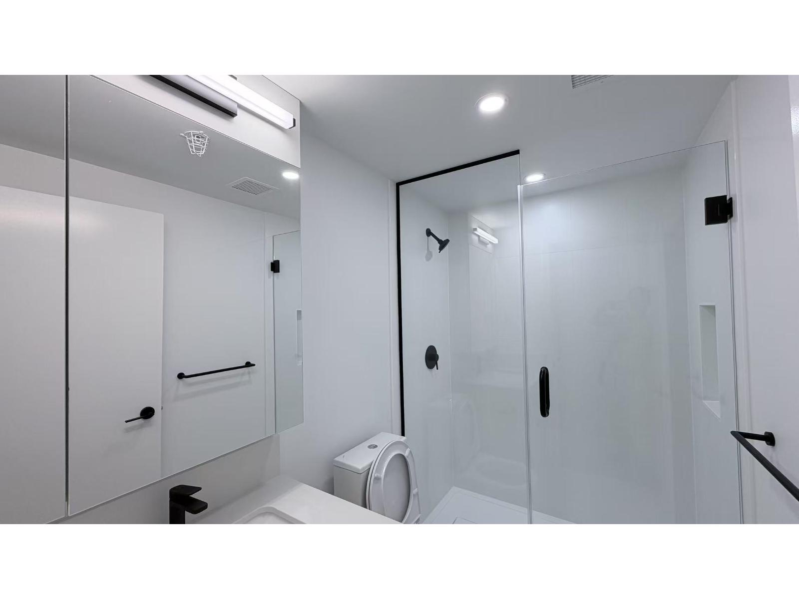 A white bathroom with a toilet, sink, and shower.