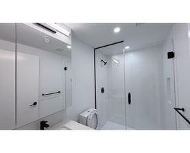 A white bathroom with a toilet, sink, and shower.