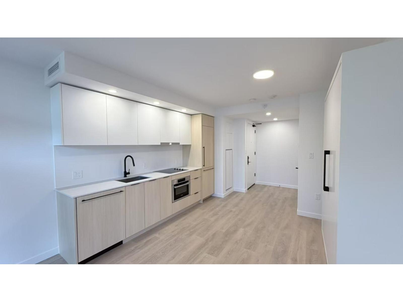 A modern kitchen with white cabinets and a wooden floor.