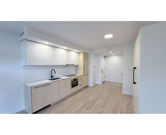 A modern kitchen with white cabinets and a wooden floor.